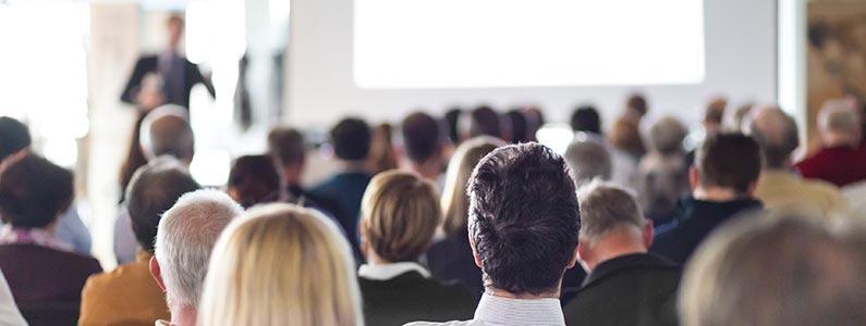people sitting in a large group facing a presentation in the distance