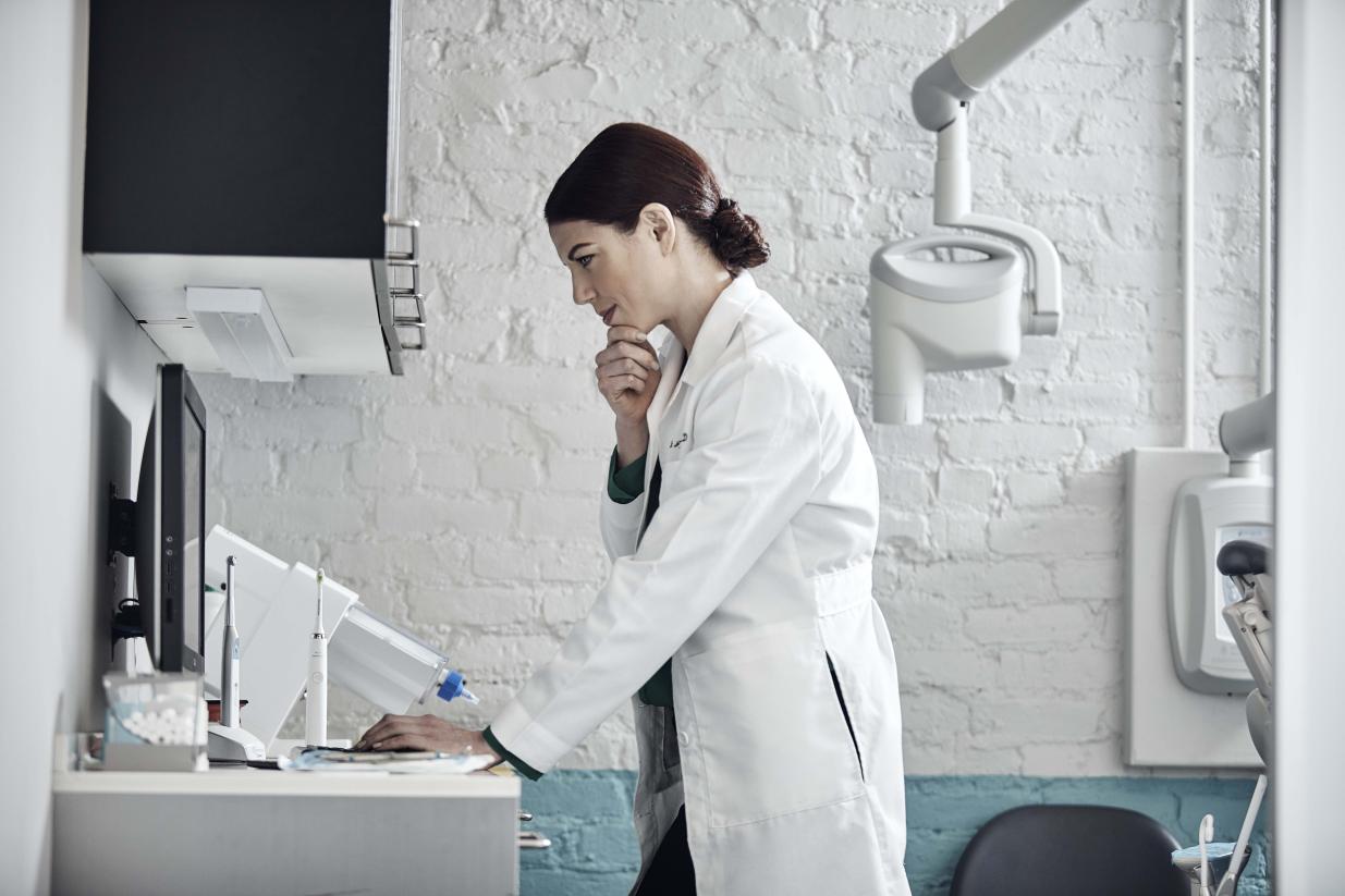 A female dentist in a dental clinic looking at a computer