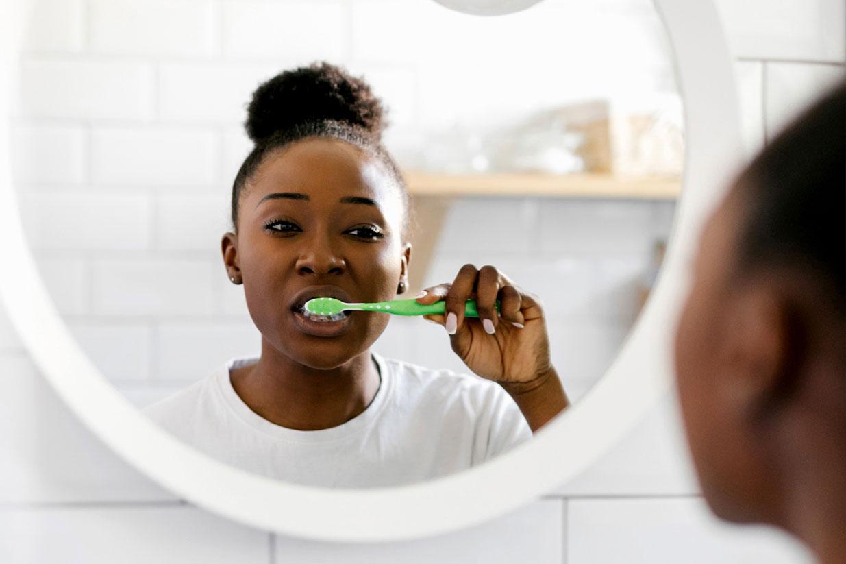 girl brushing teeth in mirror