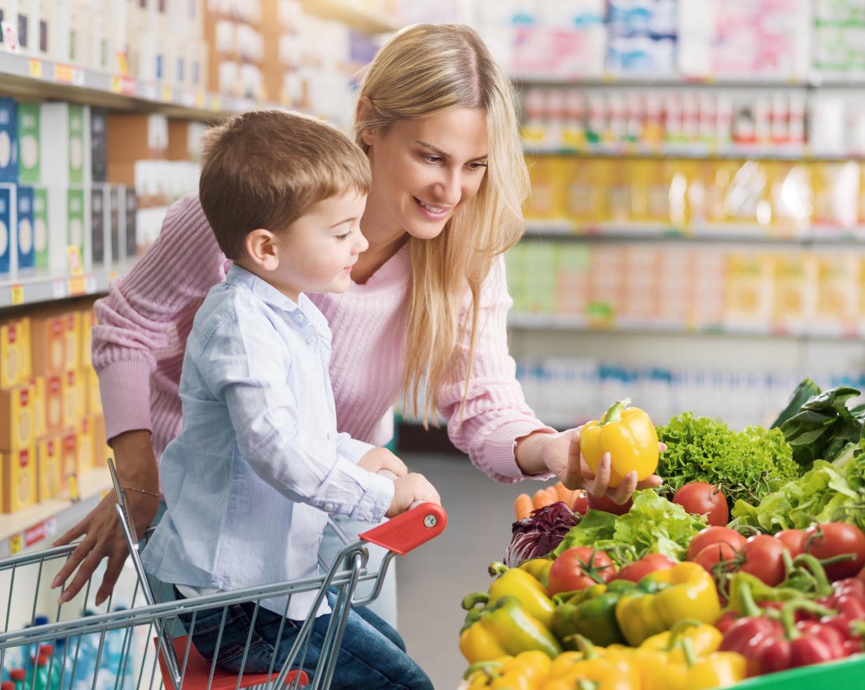 Mother and young son grocery shopping for produce.