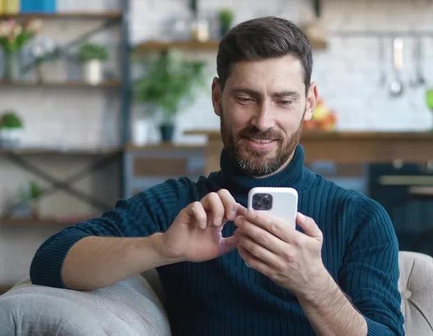 Man smiling while interacting with his phone.