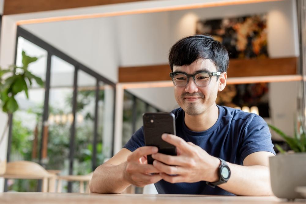 Happy man looking for a VSP network doctor on his phone.