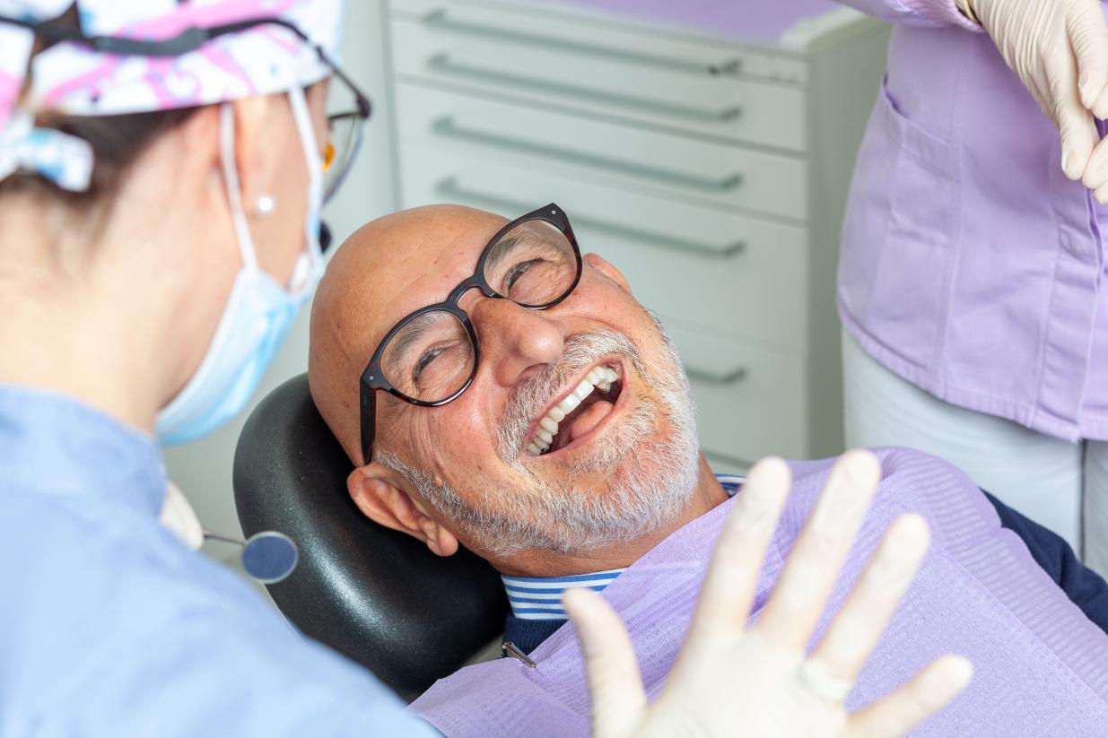 Happy senior dental patient smiling while talking to dentist.
