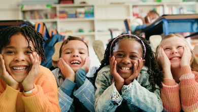 Kids laying together on the floor at school smiling with their heads in their hands