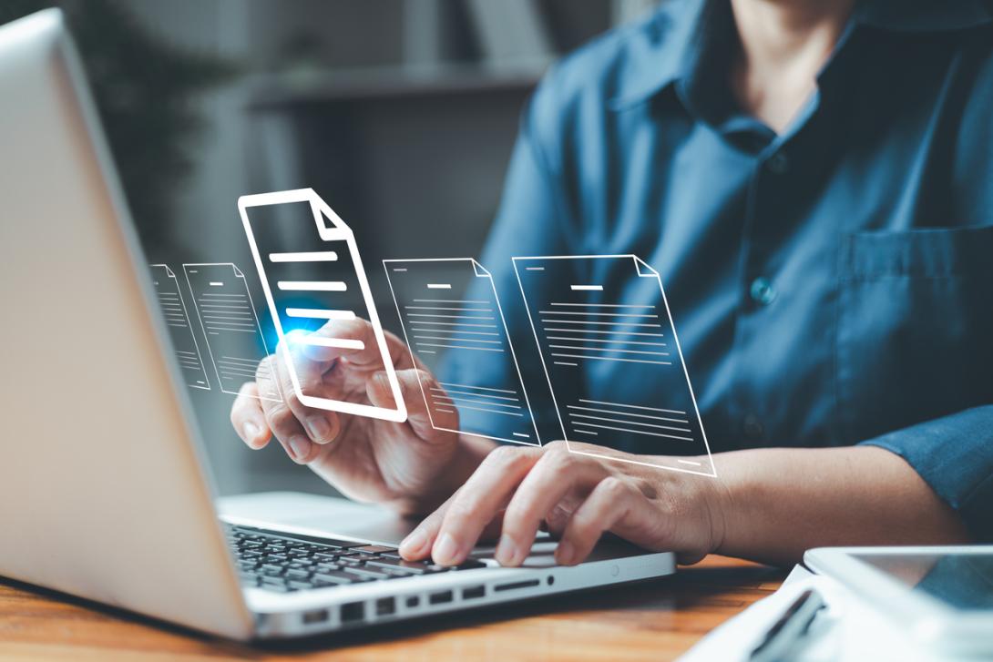 closeup of a person's hands over a laptop, with graphic icons of documents floating above